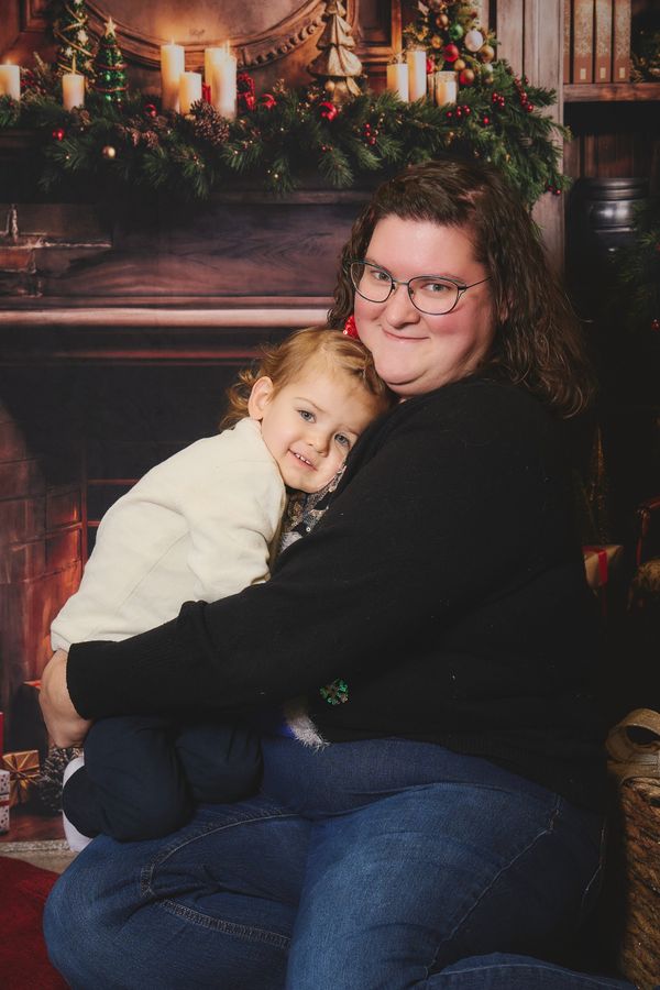 Maman qui serre sa petite fille contre elle, devant une cheminée décorée pour Noël, chez Aubert à Coudekerque-Branche
