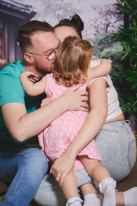 Papa et maman qui embrassent leur petite fille, décor de cerisiers, chez Orchestra à Neuville-en-Ferrain